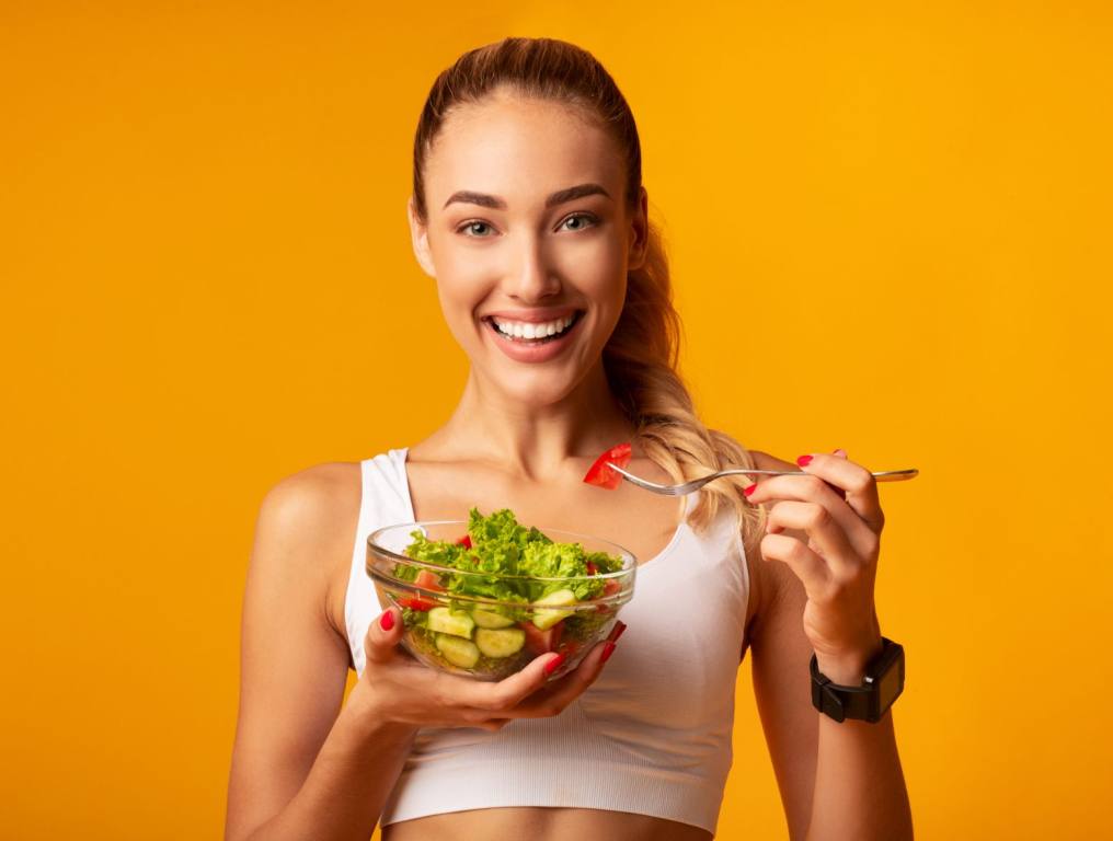 Woman eating a salad. If you're looking to tweak your diet to look younger, you might want to try this simple diet change that experts say will help you become "younger."