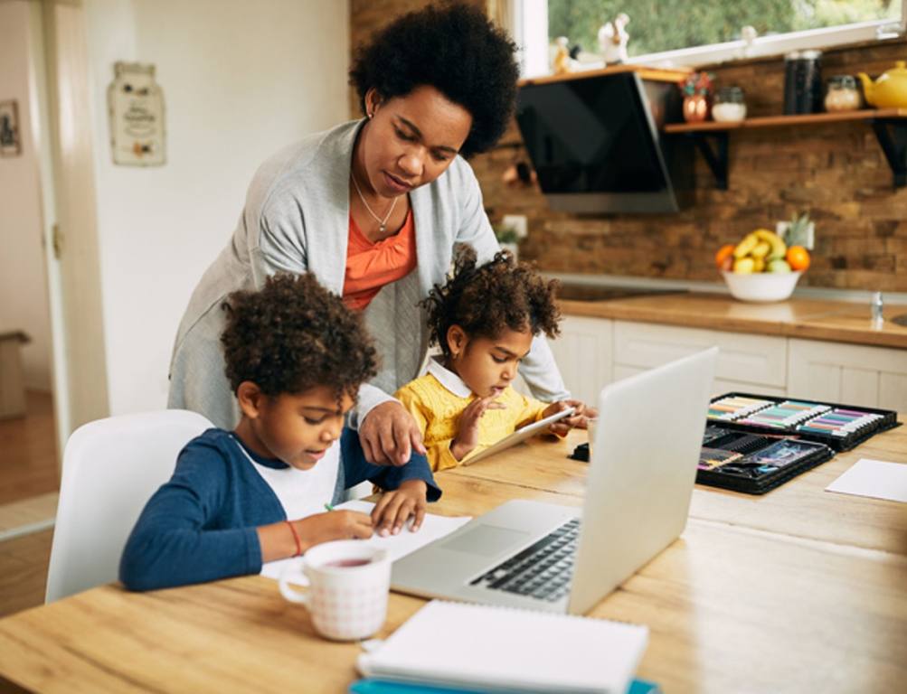 African American mother assisting her kids in learning at home.