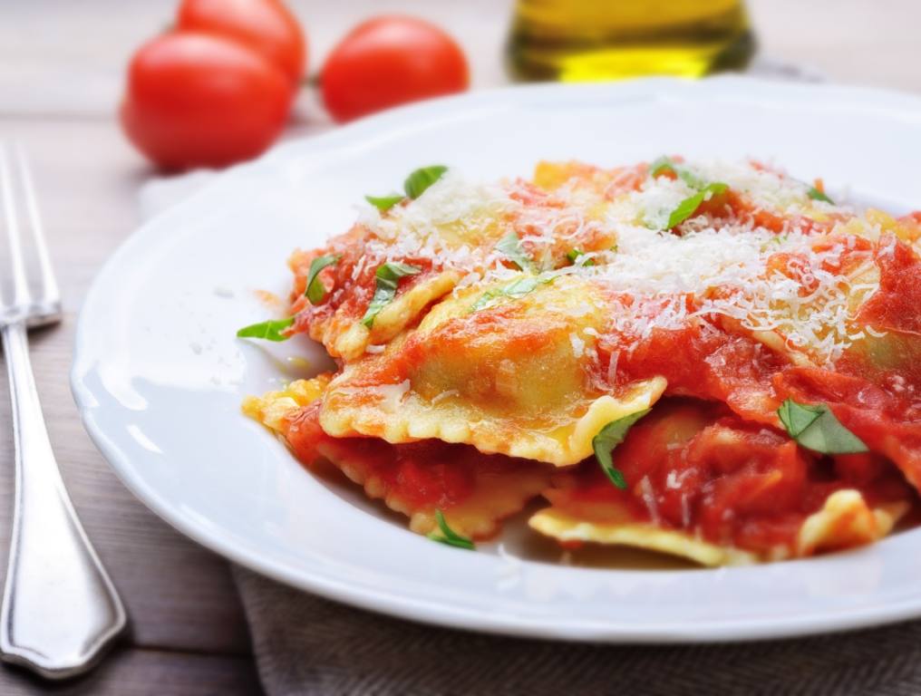 A plate of ravioli being served on a table with a white table cloth.