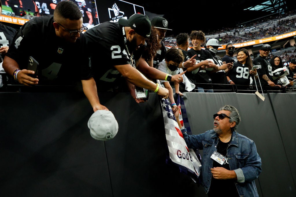 George Lopez at a Raiders game in Las Vegas, talking with fans in the stand.