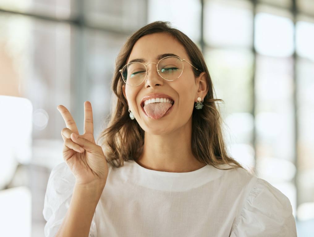 A woman with a peace sign showing off her tongue.