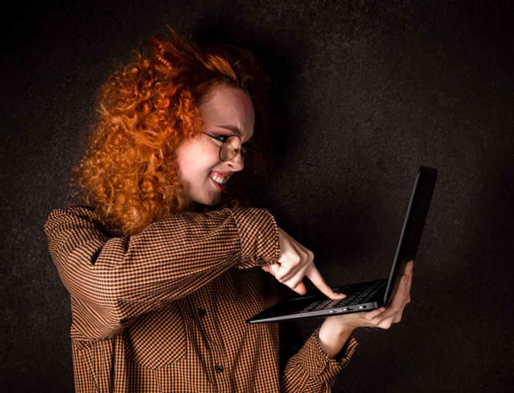 Woman clicking computer buttons against dark backdrop, unsubscribe concept.