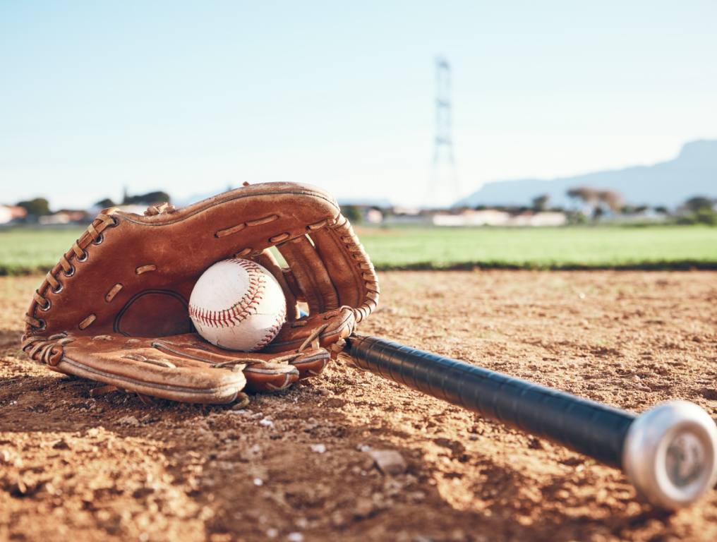 A ball and glove laying on a little league field