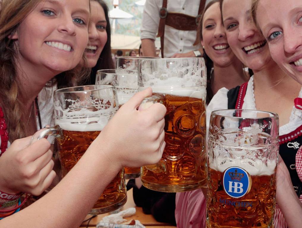 A group of young women at Hofbrauhaus Las Vegas are holding beer steins and smiling at the camera.