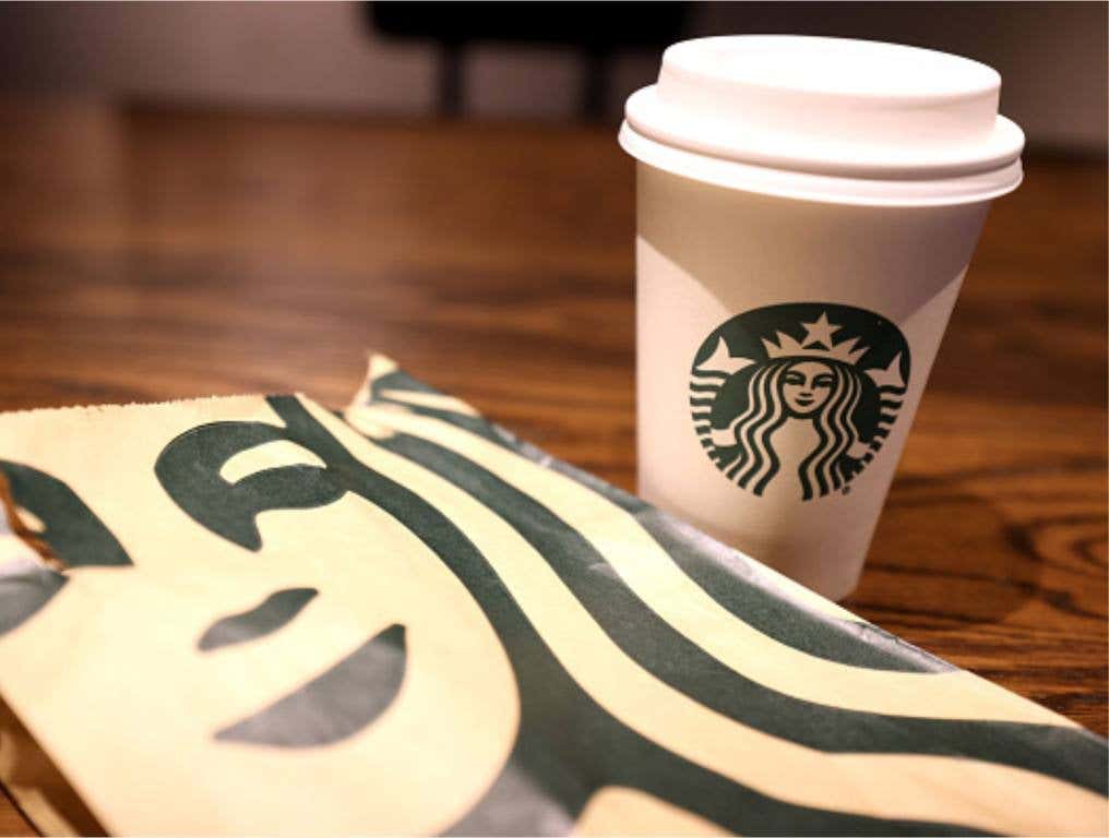 The Starbucks logo is display on a cup and bag at a Starbucks store