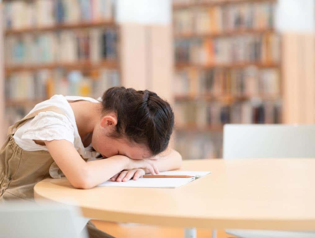 A child who needs some sleep with her heard on a table.