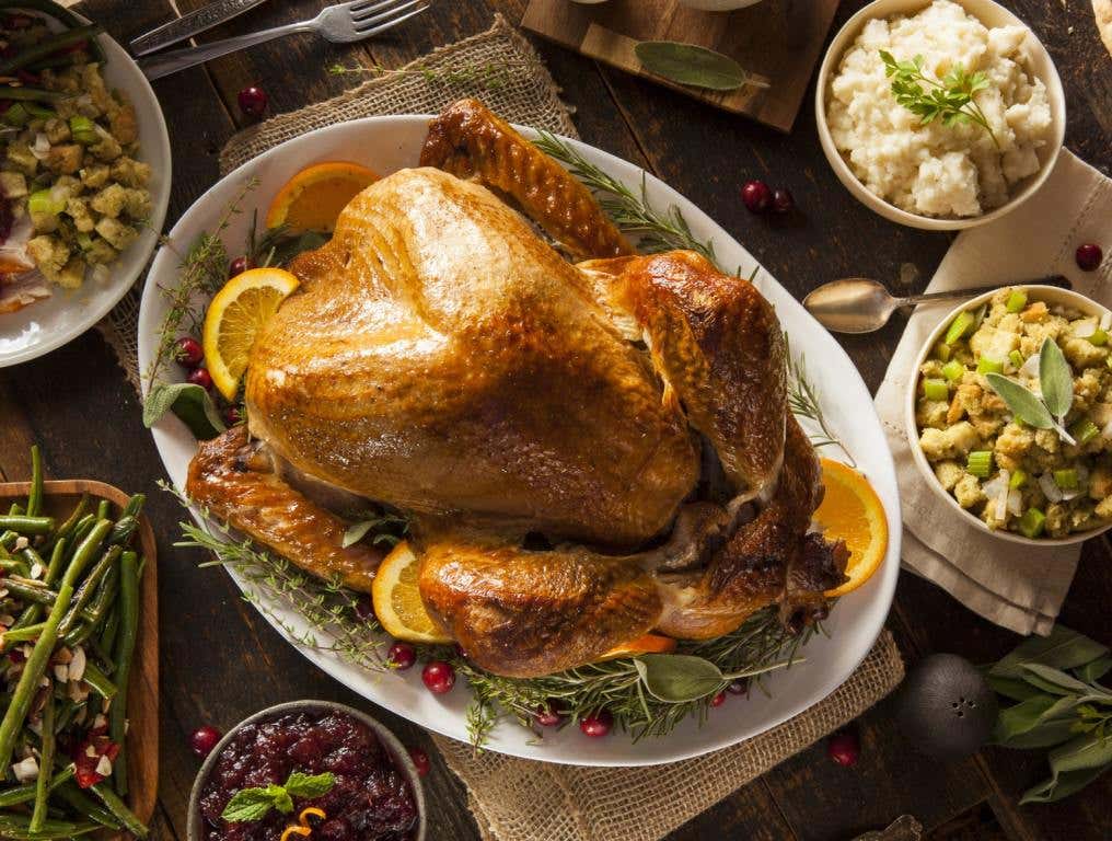 Thanksgiving dinner on a wooden table includes turkey, stuffing, mashed potatoes and cranberry sauce. Concept: free turkey dinners