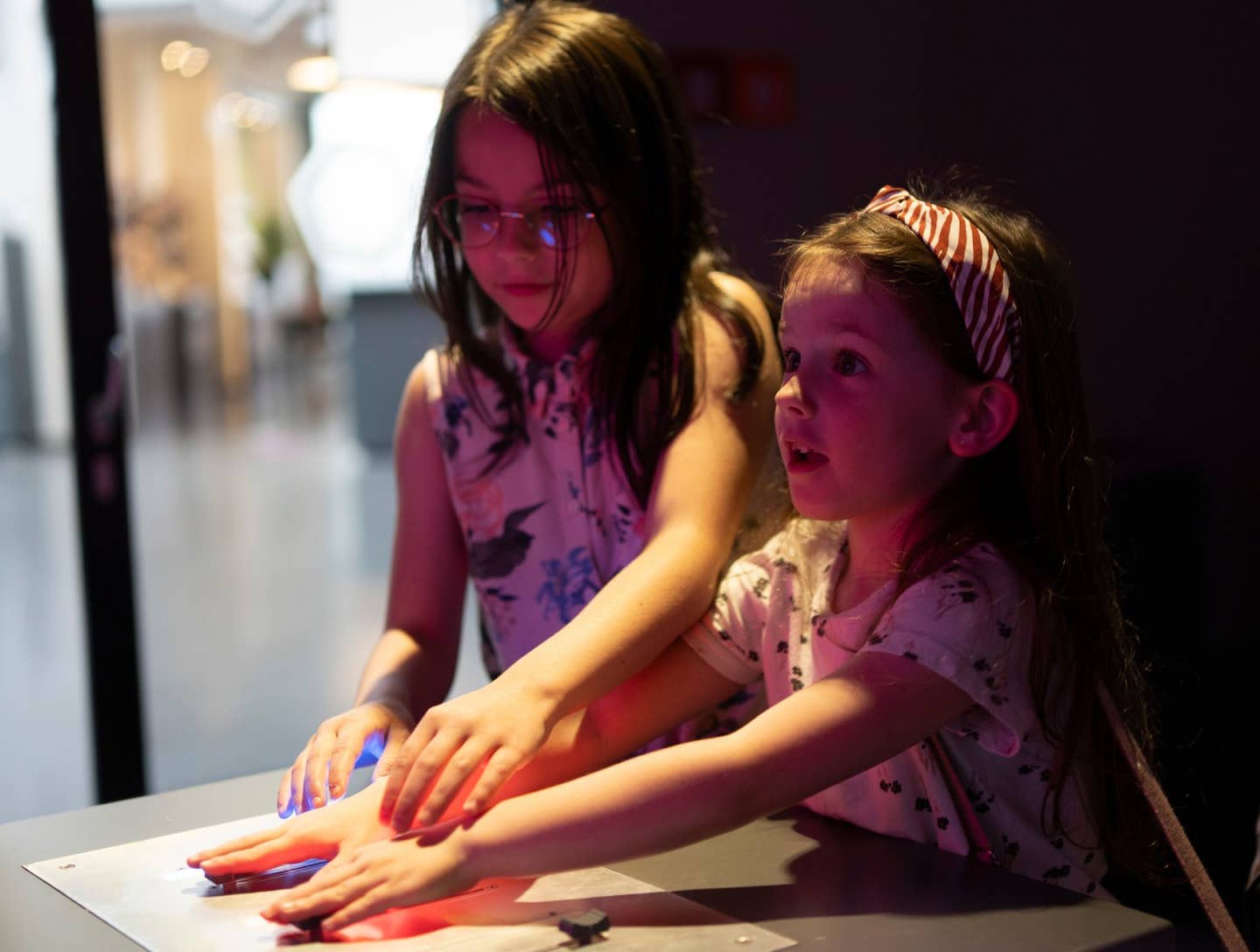 Two cute beautiful schoolgirls look up with surprise and interest in the museum. Children's education concept