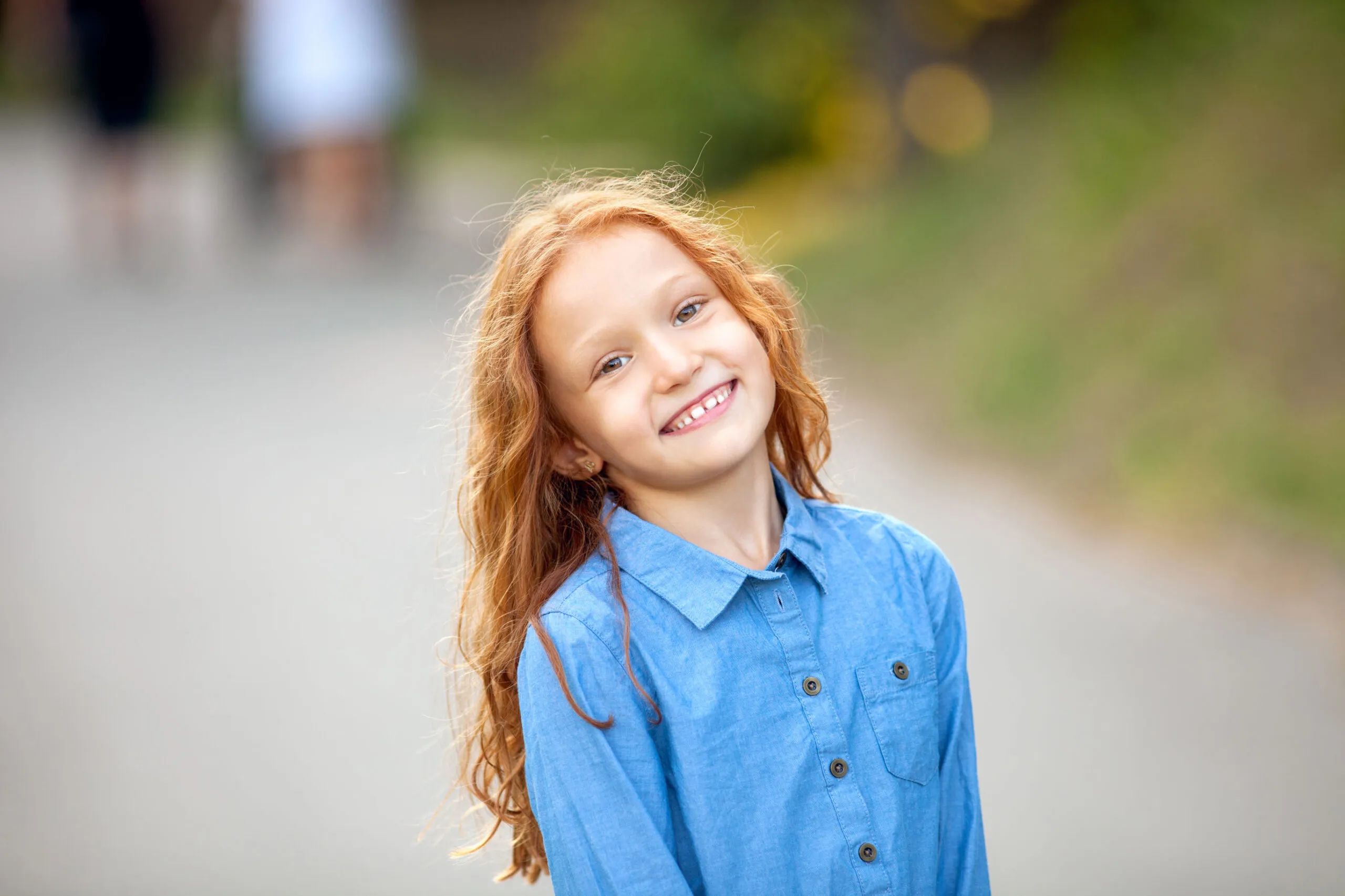 A little girl with red hair wearing a blue shirt. 