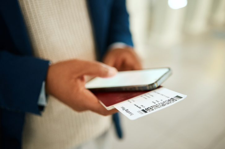 Person holding physical boarding passes while also on his phone.