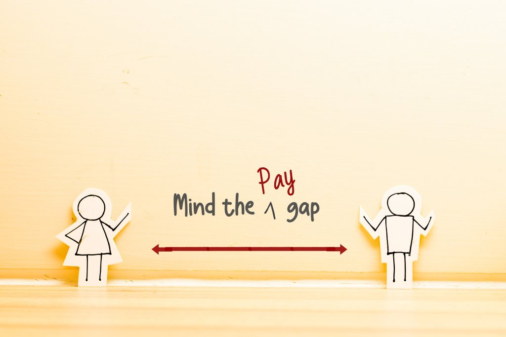 A basic cartoon stick figure woman on the left and male on the right with a line between them. Above the line reads "Mind the pay gap".