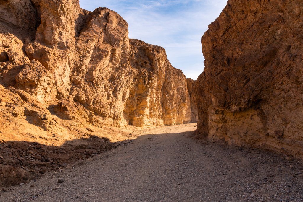 A dry river bed in Death Valley between two cliffed mountains.