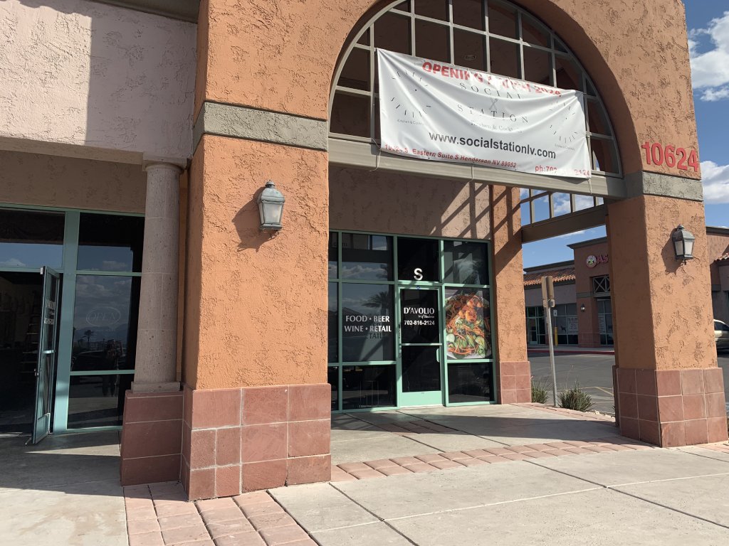 The exterior of a restaurant shows terra cotta colored archways with a temporary sign hanging from it.